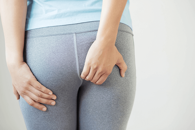 A woman scratching their anal area due to pinworm infection